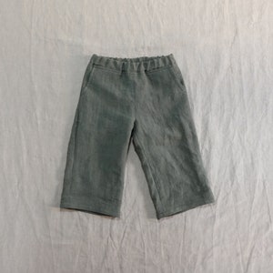 Pode incluir: Uma cal&ccedil;a de linho verde escura com c&oacute;s el&aacute;stico e bolsos laterais.