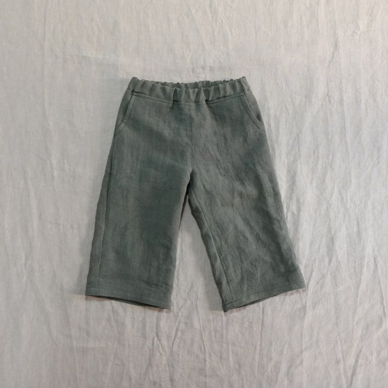Pode incluir: Uma cal&ccedil;a de linho verde escura com c&oacute;s el&aacute;stico e bolsos laterais.