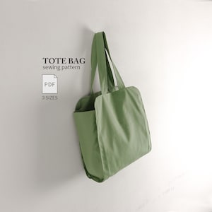 Könnte beinhalten: Eine salbeigrüne Tragetasche mit zwei Schulterriemen, präsentiert als digitales Schnittmuster. Der Text lautet TOTE BAG sewing pattern, PDF und 3 SIZES. Die Tasche hat einen einfachen rechteckigen Körper mit seitlichen Einsätzen.