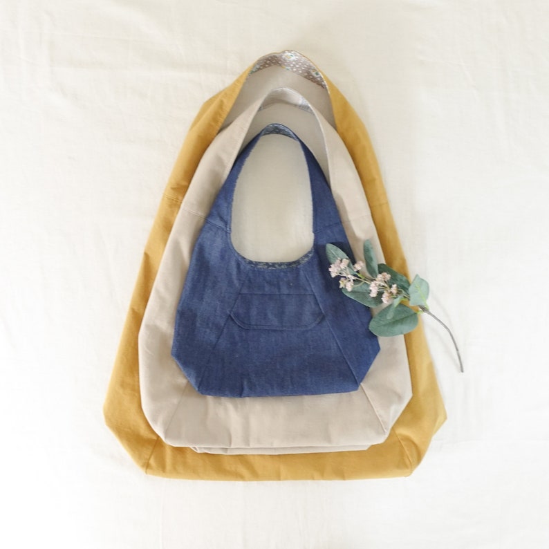 May include: Three fabric tote bags nested inside each other. The outer bag is mustard yellow, the middle bag is beige, and the inner bag is dark blue denim.
