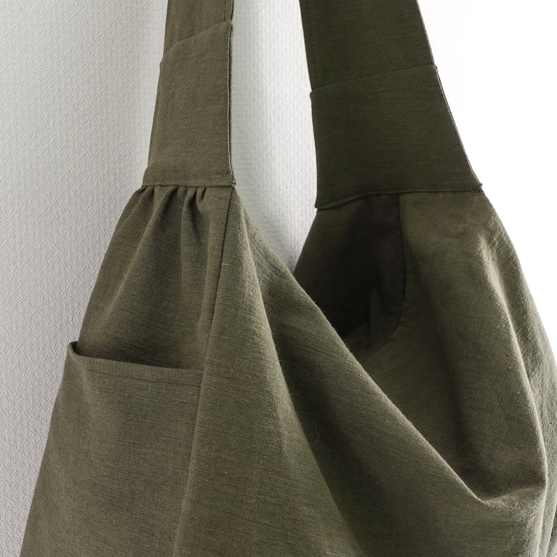 May include: A large, olive green canvas tote bag with a single strap and a pocket on the front.