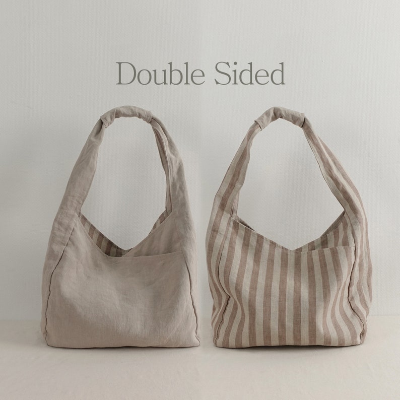 May include: Two hobo-style shoulder bags with the text Double Sided centered above them. One bag is solid beige, while the other features vertical beige and white stripes. Both bags have a single knotted handle and a visible exterior pocket.