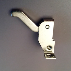 May include: Silver metal window latch with a lever handle and a mounting plate. The latch is designed to secure a window in the open position.