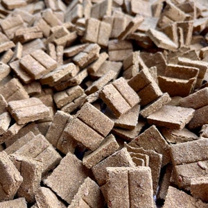 May include: A close-up view of a large pile of brown, rectangular dog treats. The treats are made of a soft, chewy material and have a slightly textured surface.