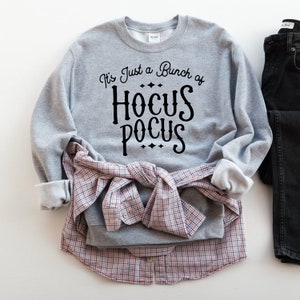Puede incluir: Sudadera gris con el texto "It's Just a Bunch of Hocus Pocus" en letras negras.