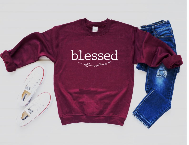 May include: Burgundy sweatshirt with the word "blessed" in white lettering with a small white floral design underneath.