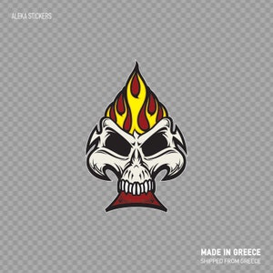Op de afbeelding: Een witte schedel met een rood en geel vlammenontwerp erop, gevormd als een schoppen speelkaart. De schedel heeft zwarte ogen en een rode mond.  "MADE IN GREECE" en "SHIPPED FROM GREECE" staan onder de schedel.