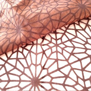 Könnte beinhalten: Zwei Stoffstücke mit einem geometrischen Muster. Der obere Stoff ist braun mit weißem Hintergrund und der untere Stoff ist weiß mit braunem Hintergrund. Das Muster ist ein sich wiederholendes Muster von Sternen.