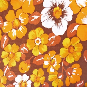 May include: A brown fabric with a repeating pattern of orange and white flowers. The flowers have a yellow centre and are surrounded by brown leaves.