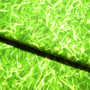 Könnte beinhalten: Grüner Stoff mit einem hellgrünen und weißen abstrakten Muster. Der Stoff hat eine strukturierte Oberfläche und ist in der Mitte gefaltet.