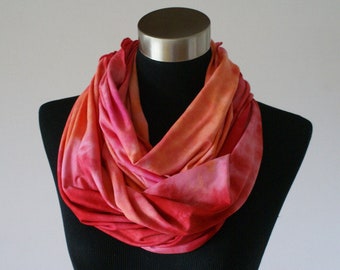 May include: A red and orange infinity scarf with a tie-dye pattern.