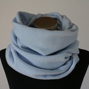 Könnte beinhalten: Ein hellblaues Fleece-Cowl-Schal, präsentiert auf einer schwarzen Schaufensterpuppe. Der weiche, geschlungene Stoff erzeugt ein warmes, gemütliches Aussehen. Dieses Winteraccessoire ist für das Tragen um den Hals konzipiert.