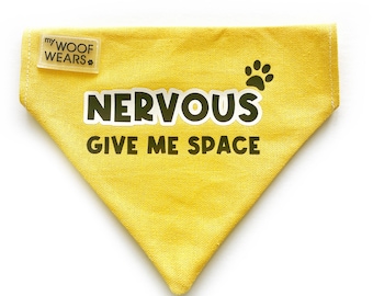 May include: Yellow dog bandana with the text "NERVOUS GIVE ME SPACE" and a paw print. The bandana has a small tag that says "my WOOF WEARS".