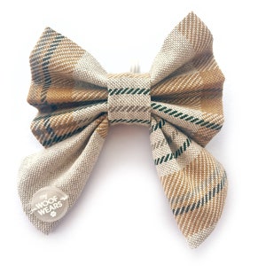 May include: A beige and brown plaid bow tie with a small white circle tag that says "my WOOF WEARS" in black text.
