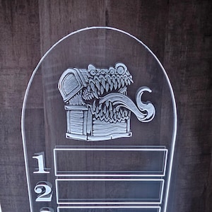 Może przedstawiać: Przezroczysta tablica wynik&oacute;w z akrylu z motywem potwora i skrzyni skarb&oacute;w. Tablica wynik&oacute;w ma dwa rzędy liczb, 1 i 2.