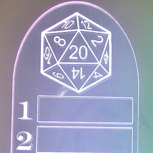 Może przedstawiać: Biały stojak akrylowy z wzorem 20-ściennej kostki do gry na g&oacute;rze. Stojak ma dwa puste miejsca oznaczone numerami 1 i 2.