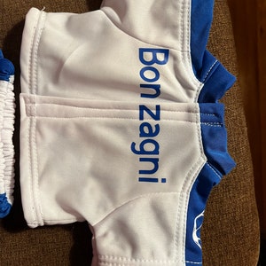 Puede incluir: Camiseta de osito de peluche blanca y azul con el texto "Bon Zagni!" impreso en la parte delantera.