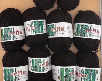 May include: A collection of black yarn balls, some with white labels featuring green bamboo illustrations and Chinese characters. The yarn is tightly wound, suggesting it's suitable for knitting or crochet projects.