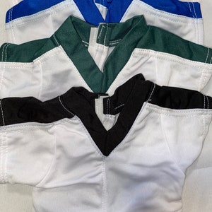 Puede incluir: Una pila de cinco camisetas de f&uacute;tbol de diferentes colores, incluyendo blanco, negro, verde, azul y rojo. Las camisetas est&aacute;n hechas de un material suave y transpirable y tienen un dise&ntilde;o cl&aacute;sico de f&uacute;tbol.