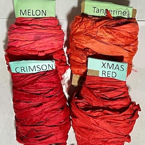 K&ouml;nnte beinhalten: Vier Spulen mit zerknittertem Band in den Farben Melon, Tangerine, Crimson und Xmas Red. Jede Spule hat ein hellgr&uuml;nes Papieretikett mit dem entsprechenden Farbnamen in schwarzer Schrift und ist mit strukturiertem, stoffartigem Band umwickelt.