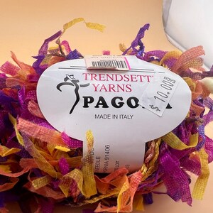 Könnte beinhalten: Ein Knäuel mehrfarbiger Wolle mit einem Etikett mit der Aufschrift "Trendsett Yarns Pagoda Made in Italy" und einem Preisschild mit der Aufschrift "10,00 € pro Stück".