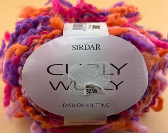 Könnte beinhalten: Ein Knäuel Sirdar Curly Wulley Strickgarn mit einer lebendigen Mischung aus orangefarbenen, violetten und rosafarbenen strukturierten Fasern. Ein weißes Papieretikett umschließt die Mitte und zeigt den Markennamen, den Produkttitel und einen Preisaufkleber.