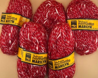 May include: A collection of red and white yarn skeins. Each skein is wrapped with a yellow label that reads "Schachenmayr nomotta MARILYN". The yarn has a textured appearance, with the red and white fibers intertwined.