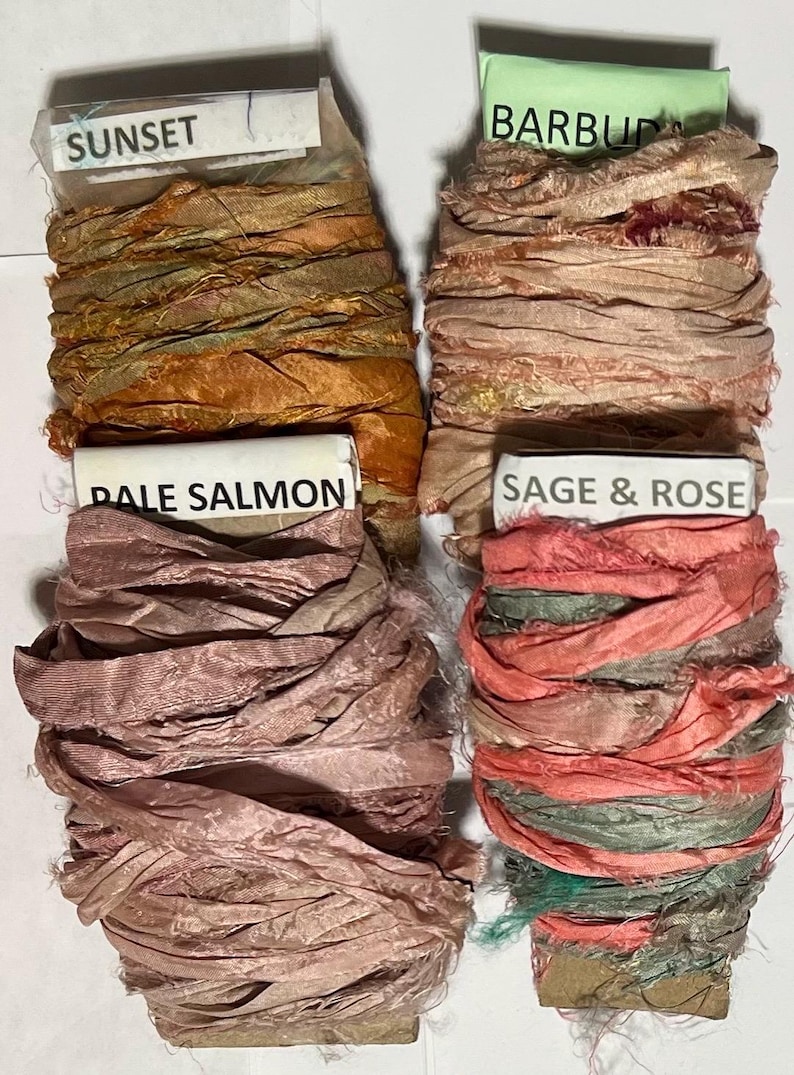 K&ouml;nnte beinhalten: Vier Spulen aus zerknittertem Seidenband mit ausgefransten Kanten. Die obere linke Spule ist mit SUNSET in Orange- und Goldt&ouml;nen beschriftet. Die obere rechte Spule ist mit BARBUDA in Beige beschriftet. Unten links steht PALE SALMON, unten rechts SAGE & ROSE.