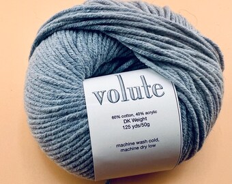 May include: A ball of gray yarn labeled "volute" with text indicating it is 60% cotton, 40% acrylic, DK weight, 125 yards/50g. The label also states the yarn is machine washable in cold water and can be machine dried on low.