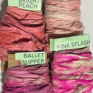 K&ouml;nnte beinhalten: Vier Spulen aus zerknittertem Seidenband in verschiedenen Rosa- und Pfirsicht&ouml;nen. Jede Spule hat ein hellgr&uuml;nes Etikett mit dem Text: Bright Peach, Shell Pink, Ballet Slipper und Pink Splash. Die B&auml;nder haben eine strukturierte, ausgefranste Optik.