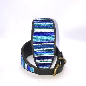 K&ouml;nnte beinhalten: Ein blaues und wei&szlig;es Perlen-Hundehalsband mit braunem Ledergrund und einer Messing-Schnalle.