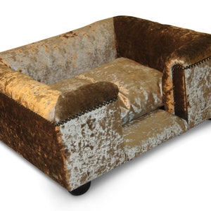 May include: A brown and gold dog bed with a raised edge and a plush, velvety texture. The bed has a rectangular shape and is designed for a pet to sleep comfortably.