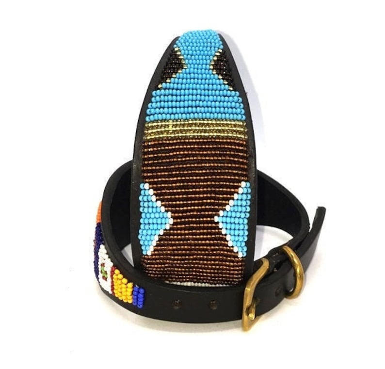 K&ouml;nnte beinhalten: Ein schwarzes Lederhundekragen mit einem bunten Perlenmuster. Das Perlenmuster zeigt blaue, braune, wei&szlig;e und goldene Perlen in einem geometrischen Muster.