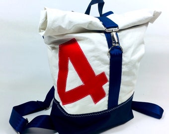 May include: White backpack with a roll-top closure, featuring a large red number "4" and navy blue accents. The bag has adjustable navy blue shoulder straps and a silver-tone clasp. The bottom of the bag is navy blue.