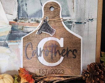 May include: A wooden cutting board shaped like a cow's head with the text "Carothers Est. 2023" on it.