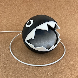 May include: A black and white 3D printed Google Home Mini speaker cover shaped like a Pac-Man character with an open mouth.