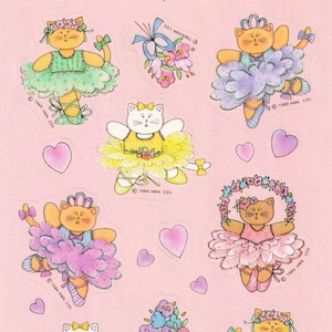 May include: A sheet of stickers featuring seven adorable cartoon cats dressed as ballerinas. Each cat wears a different colored tutu and has a different hairstyle. The stickers are on a pink background with hearts and flowers.