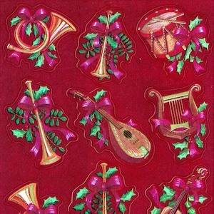Puede incluir: Nueve pegatinas navideñas vintage con instrumentos musicales decorados con acebo y lazos rojos. Los instrumentos incluyen una trompeta, un arpa, un violín, una mandolina y un tambor.