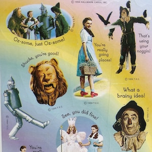 May include: Sheet of stickers featuring characters from The Wizard of Oz. Includes images of Dorothy, the Scarecrow, the Tin Man, the Cowardly Lion, the Wicked Witch, and Glinda. Text includes phrases like "Oz-some" and "You're really going places!"