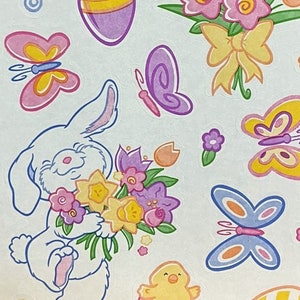 May include: A sheet of Easter stickers featuring a white bunny holding a bouquet of yellow, pink, and purple flowers, a chick hatching from an egg, butterflies, and eggs with polka dots and stripes.