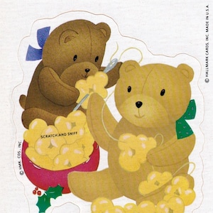 May include: Two brown teddy bears are making a garland of yellow flowers. The bear on the left is holding a needle and thread. The bear on the right is wearing a green and white bow. The text on the card reads "Special times are twice as fun When shared with friends like you! Merry Christmas!"
