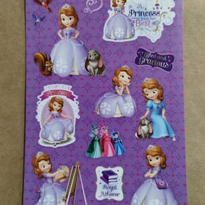 May include: A sheet of stickers featuring the Disney character Sofia the First in various poses. The stickers are primarily purple, with images of Sofia in her princess dress, along with other characters and text like "Royal Achiever".