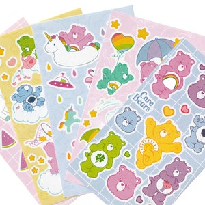 May include: A set of five sticker sheets featuring Care Bears characters. Each sheet has a different theme, including a unicorn, a rainbow, a cloud, and a watermelon. The sheets are printed on white paper with a grid pattern.