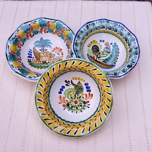 Puede incluir: Tres cuencos de cerámica coloridos con bordes festoneados. Cada cuenco presenta un diseño diferente pintado a mano con un gallo, un pájaro y una gallina. Los cuencos tienen un fondo blanco con acentos amarillos, verdes, azules y naranjas.
