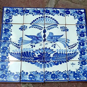 May include: A collection of ceramic tiles with a blue and white floral and bird design. The tiles are arranged together, showcasing a cohesive pattern. The artwork features detailed illustrations of birds and flowers, creating a decorative and artistic display.