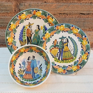 May include: A set of three hand-painted ceramic dishes. The set includes two plates and a bowl, all featuring a white background with colorful illustrations of couples in traditional attire. The rims are decorated with a floral pattern in yellow, green, and orange.
