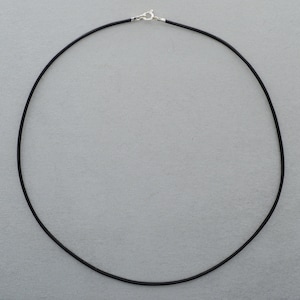 Könnte beinhalten: Eine schwarze Lederkordelkette mit einem silbernen Verschluss.