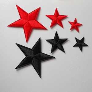 Könnte beinhalten: Fünf gestickte Bügelbilder in Form von Sternen. Zwei rote Sterne und drei schwarze Sterne.