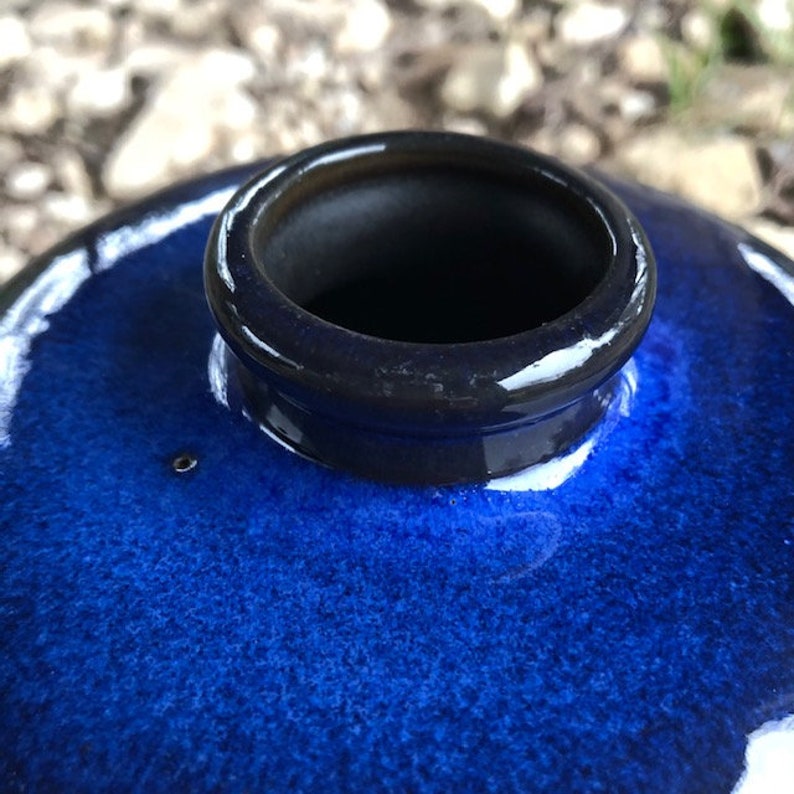 May include: A dark blue ceramic vase with a wide opening and a glossy finish.