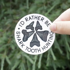 May include: White round sticker with the text "I'd rather be shark tooth hunting" and a graphic of five shark teeth.